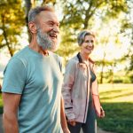 Seniors souriants marchant dans un parc, profitant de la sérénité offerte par une mutuelle senior pas chère et bien adaptée.